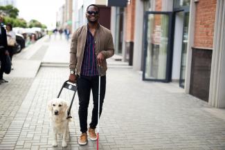 Blind man walking down street with guide dog
