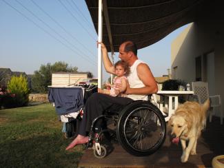 Man on porch in wheelchair with daughter and dog